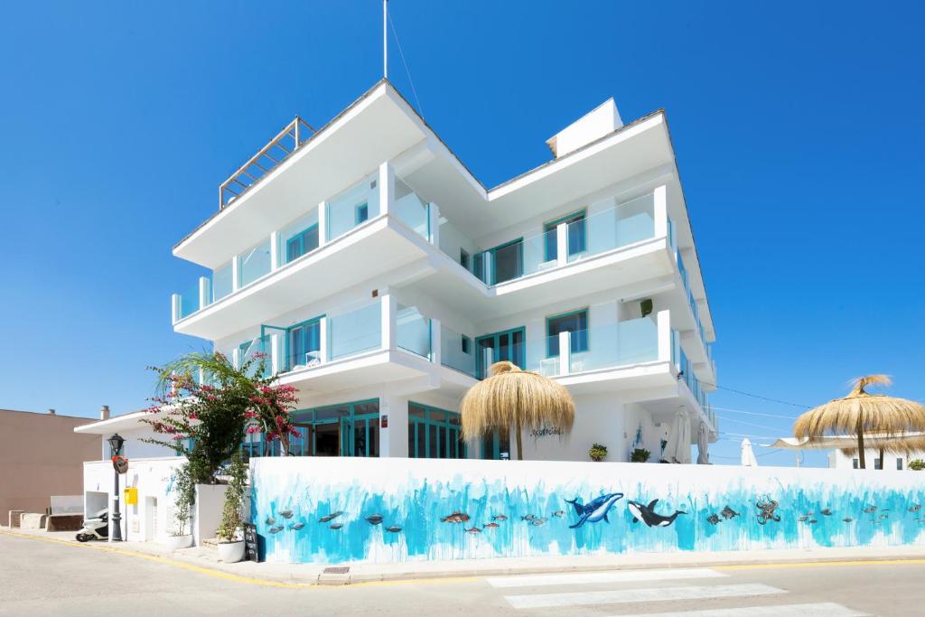Un edificio blanco con delfines azules. en Hostal Cala Llombards, en Cala Llombards