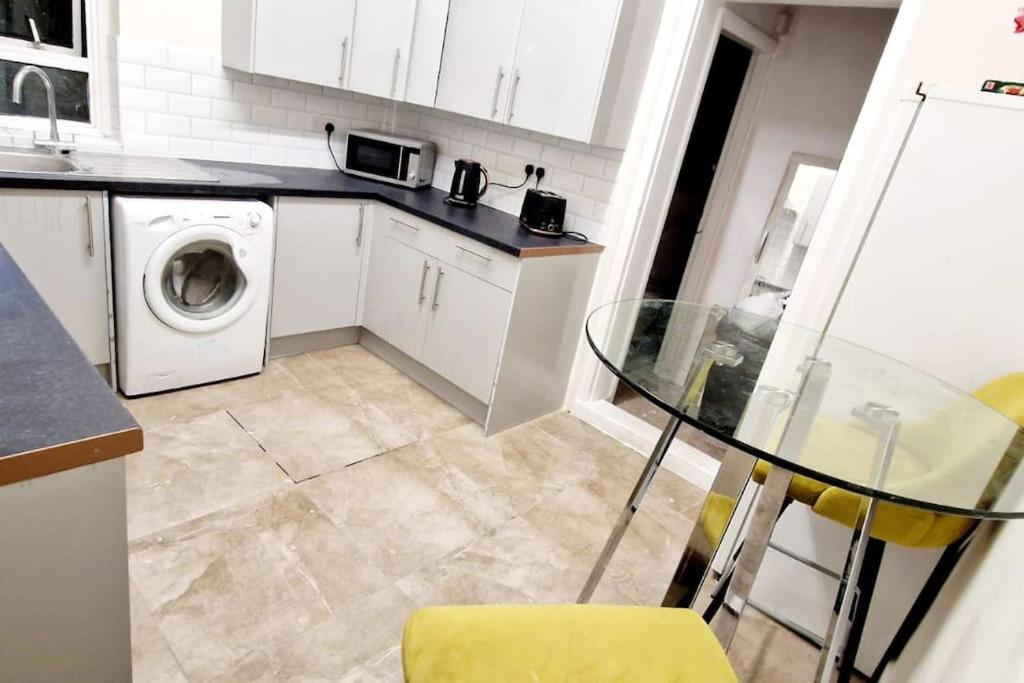 cocina con mesa de cristal y lavadora en Two Bedroom Maisonette in Erith en Dartford