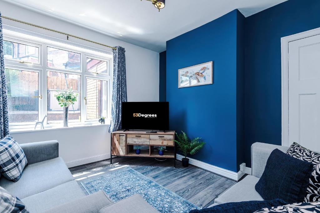 Il comprend un salon doté de murs bleus et d'une télévision. dans l'établissement Modern 3-Bed house in Stoke by 53 Degrees Property, Ideal for Business & Long Stays - Sleeps 6, à Stoke-on-Trent