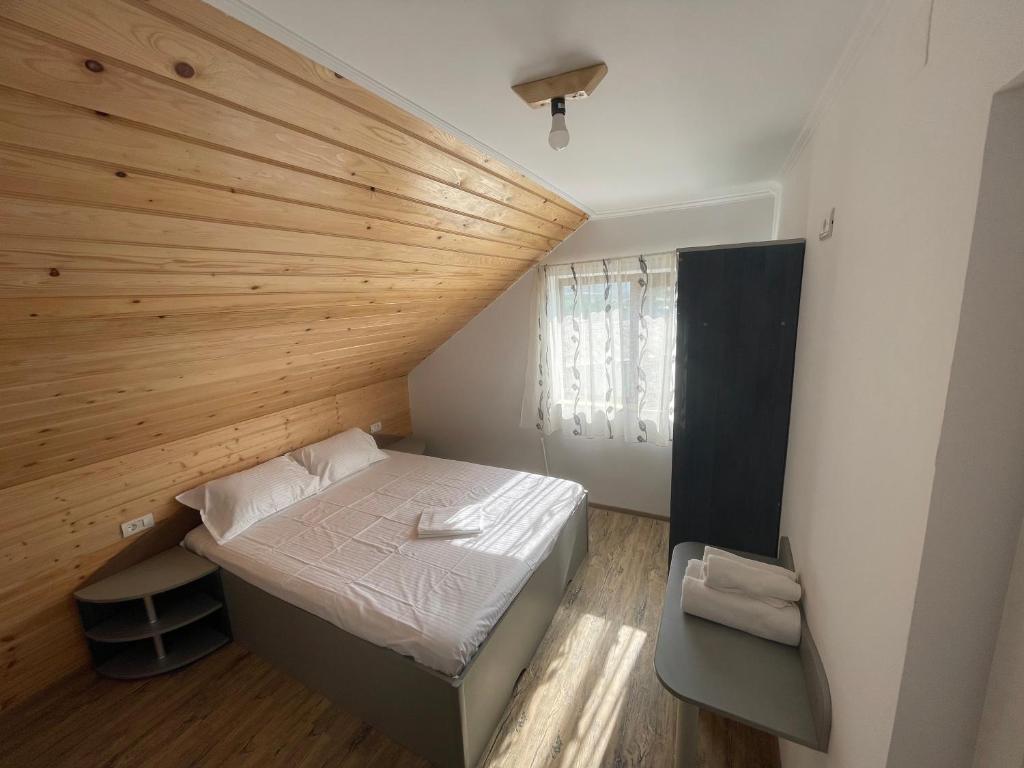 Habitación pequeña con cama y techo de madera. en Casa Enisala, en Enisala