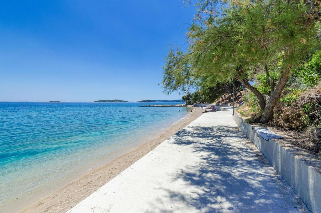 a beach with trees and the ocean on a sunny day at apartmani stefan in Orebić