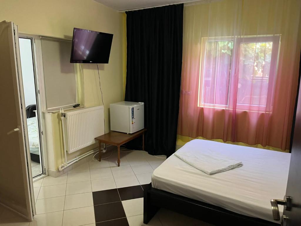 1 dormitorio con 1 cama y TV en la pared en Vila Vio 2 camere independente, en Eforie Nord