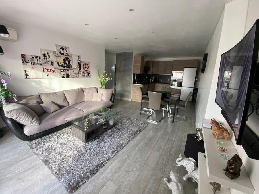 a living room with a couch and a tv and a kitchen at Charmant appartement T3 la Ciotat in La Ciotat