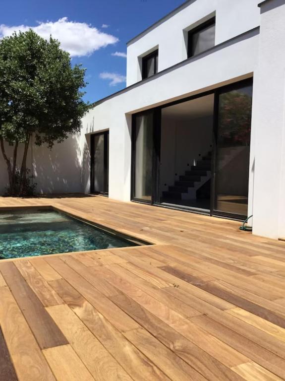 una terraza de madera con piscina frente a una casa en Villa avec piscine bord de mer CARNON en Carnon-Plage