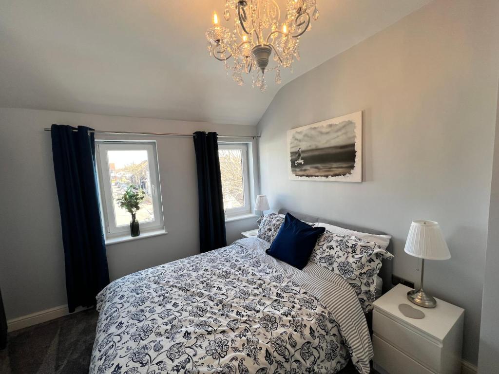 a bedroom with a bed and a chandelier and two windows at The Wedge in Southend-on-Sea