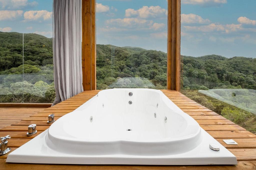a bath tub in a room with a large window at Chalés de luxo na Serra Catarinense - VST in Annitapolis