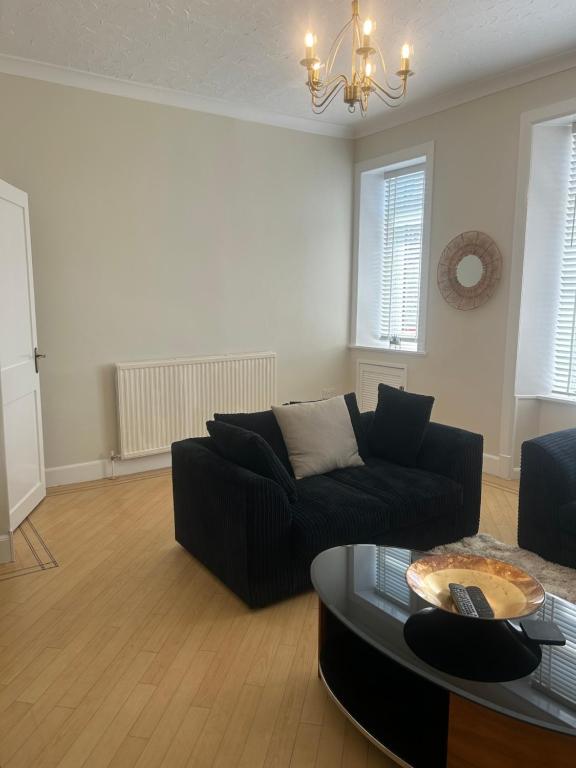 a living room with a black couch and a table at 1L Albert Place in Polmont