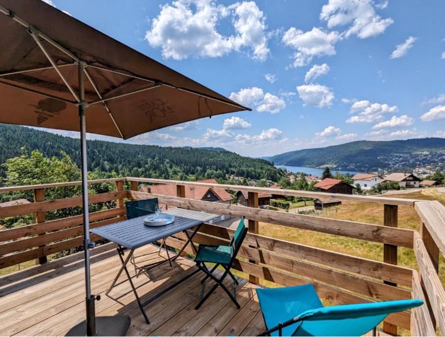 une table et des chaises sur une terrasse avec un parasol dans l'établissement La Chouette-Appartement, à Gérardmer
