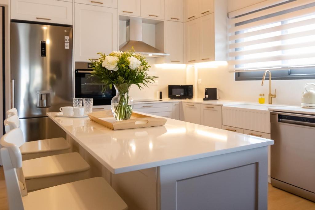 a white kitchen with a vase of flowers on a counter at ANESIS Luxury Apartment in Lefkada