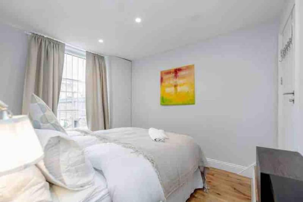 a white bedroom with a bed and a window at Beautiful 3 bedrooms apartment in London