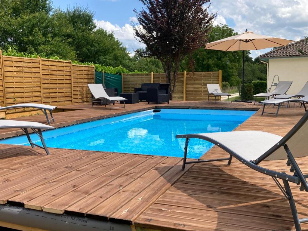 - une piscine avec des chaises et un parasol sur une terrasse en bois dans l'établissement Les escales Périgourdines, Lucie, 3 étoiles, à Trémolat