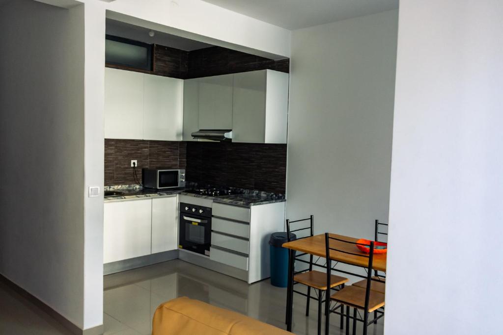 a kitchen with white cabinets and a table with chairs at Apartamento Novo, Brand New Apartament T1, Cidadela, Praia, Cabo Verde in Praia