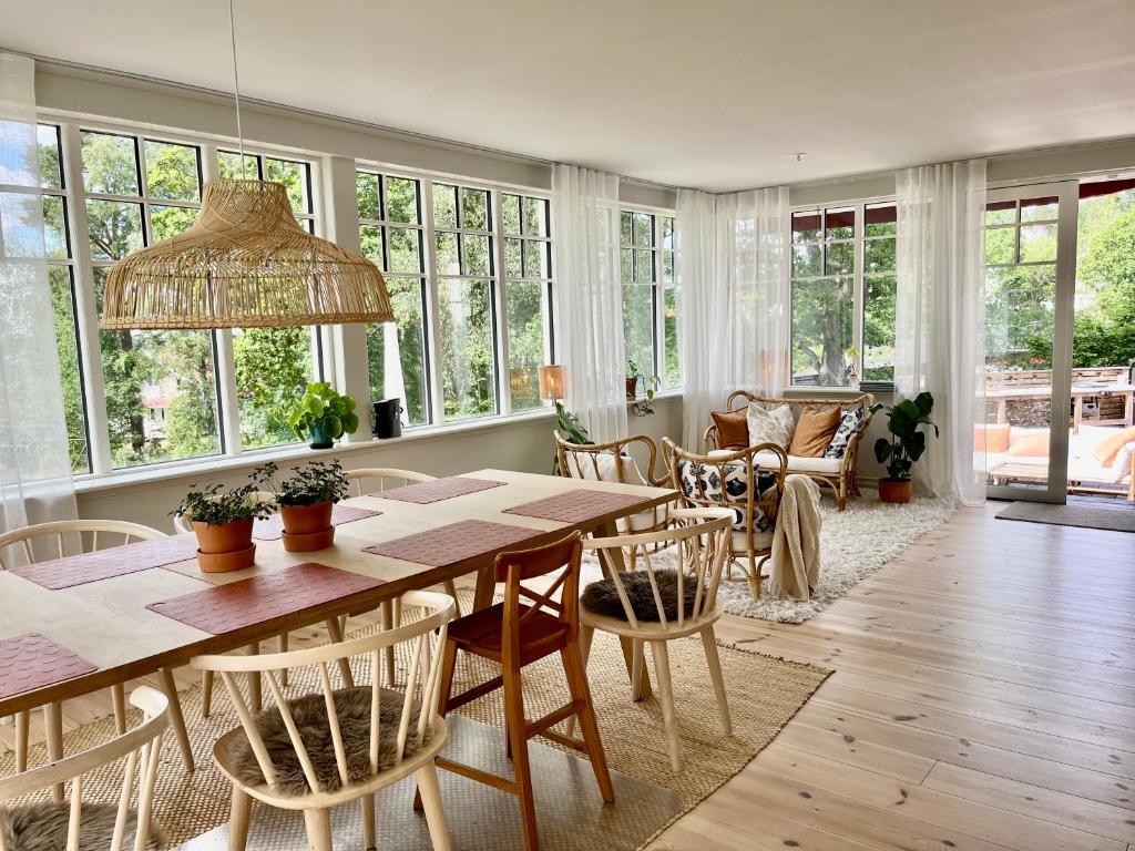 - une salle à manger avec une table, des chaises et des fenêtres dans l'établissement Villa Rye Street Kolmården, à Kolmården