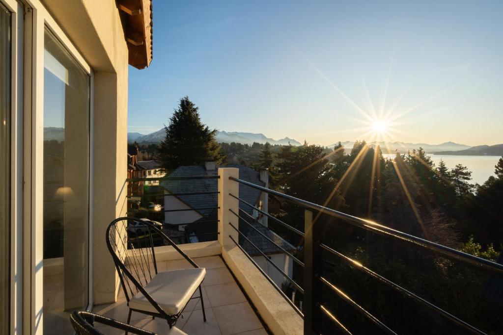 balcón con silla y vistas al sol en NBH Lacus Boutique Hotel en San Carlos de Bariloche