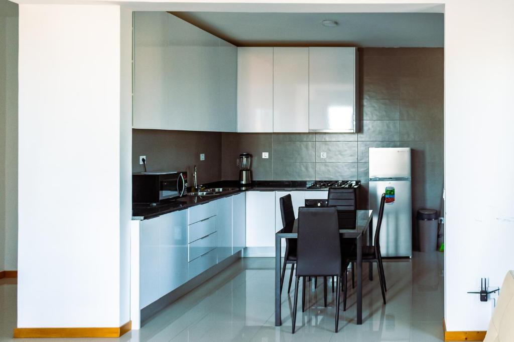 a kitchen with white cabinets and a table and chairs at Beautiful and brand new 2 bedrooms apartment/ Magnifico e novo apartamento T2 in Praia
