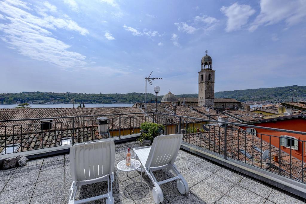 a balcony with two chairs and a clock tower at Fantoni luxury Loft in Salò