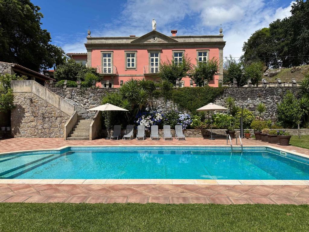 una piscina di fronte a una grande casa di Solar do Conde a Paredes de Coura