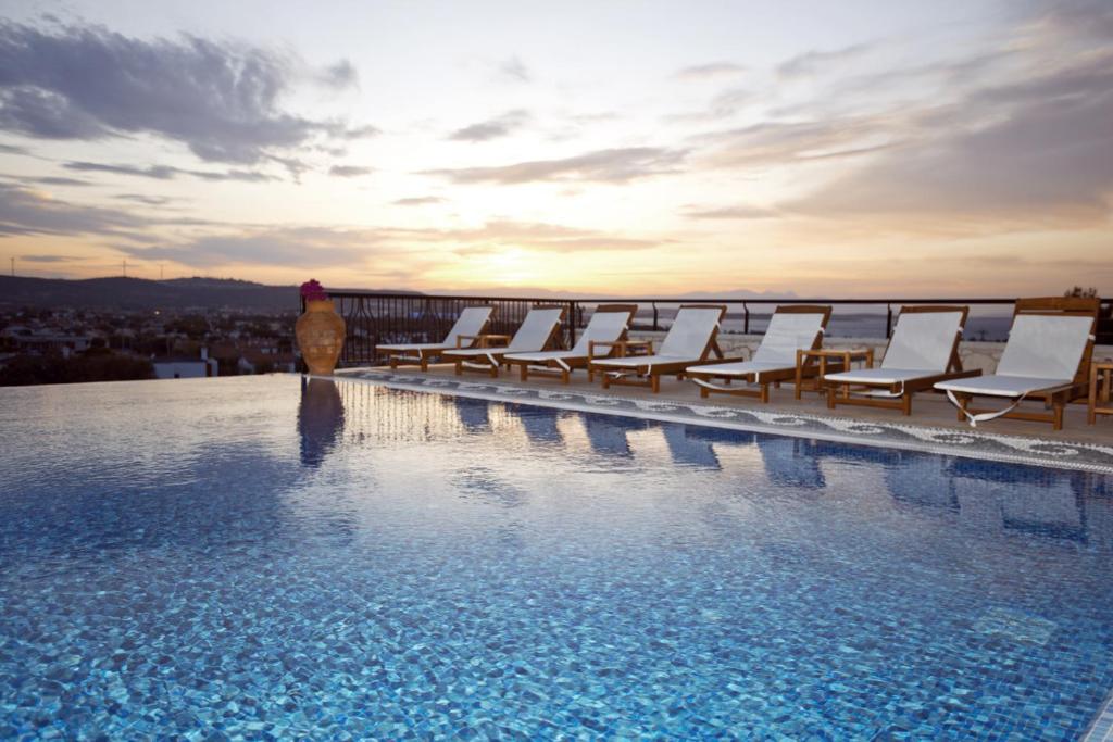 a hotel swimming pool with chairs and the sunset at Alacati VillaRenk in Alacati