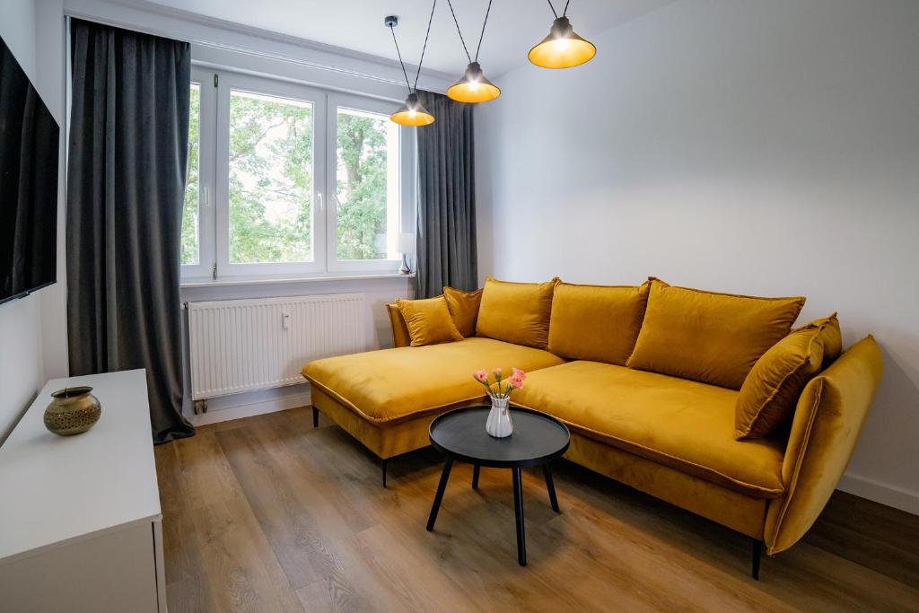 salon z żółtą kanapą i stołem w obiekcie Apartament Alpaka 1 w Lidzbarku Warmińskim