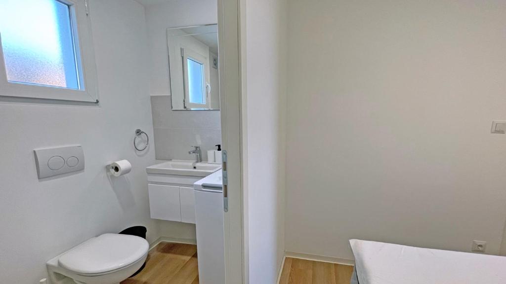 a white bathroom with a toilet and a sink at Cottage JANICE Beach in Pakoštane