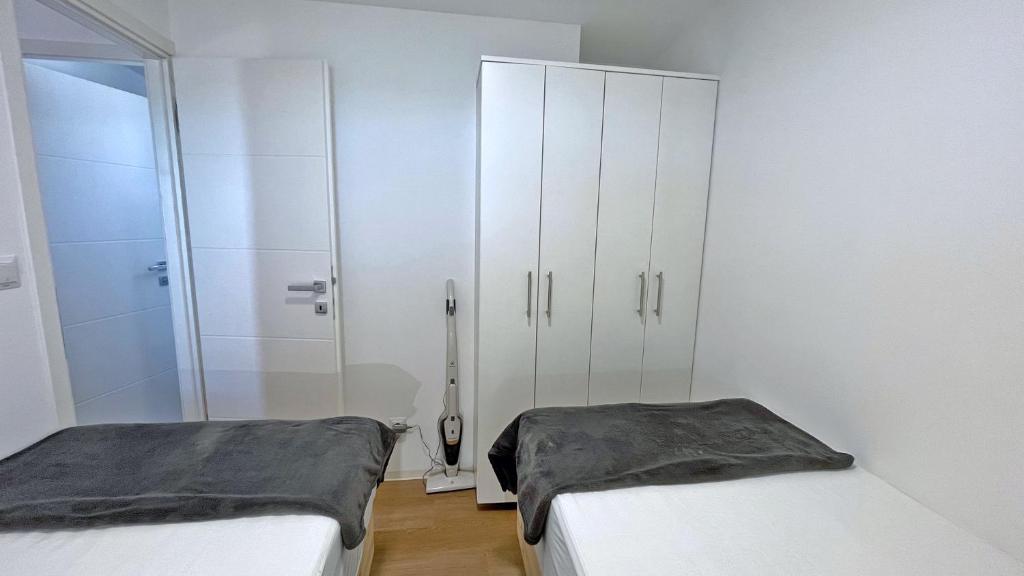 a white bedroom with two beds and a closet at Cottage JANICE Beach in Pakoštane