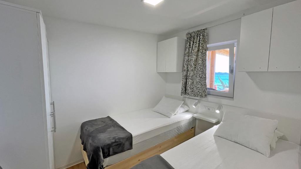 a small white room with a bed and a window at Cottage JANICE Beach in Pakoštane