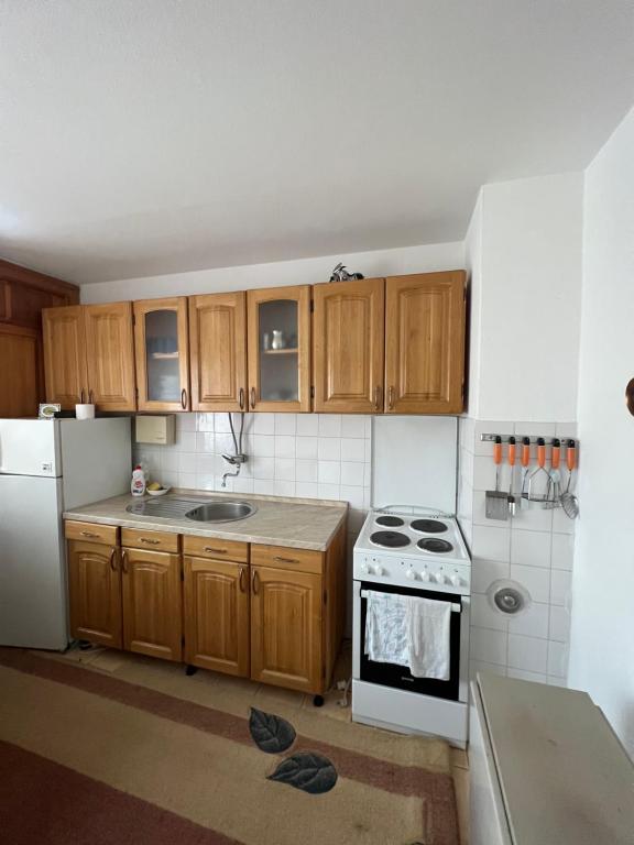 La cuisine est équipée de placards en bois et d'une cuisinière blanche. dans l'établissement Travnik Apartment, à Travnik