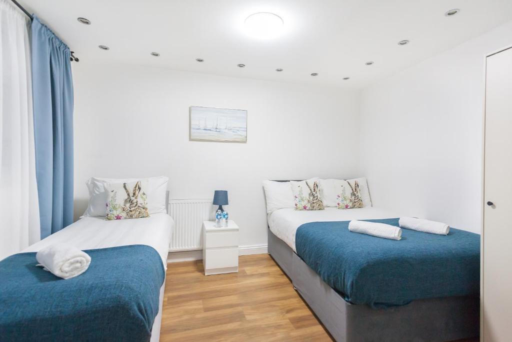 twee bedden in een kamer met blauw en wit bij Holloway Budget Apartment - 1 Minute to Emirates Stadium - Next to Station - City Center in Londen
