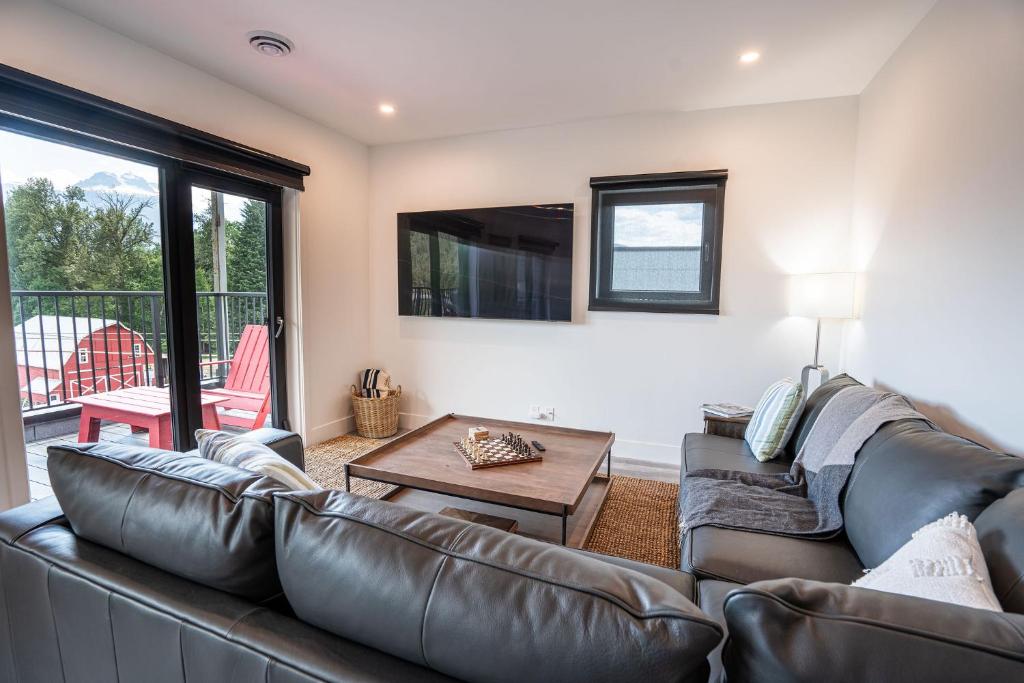 a living room with a leather couch and a table at Stoke House by Revelstoke Vacations in Revelstoke