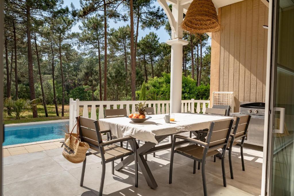 - une table et des chaises sur une terrasse avec piscine dans l'établissement Belle villa familiale rénovée dans cadre exceptionnel-AG15, à Lacanau
