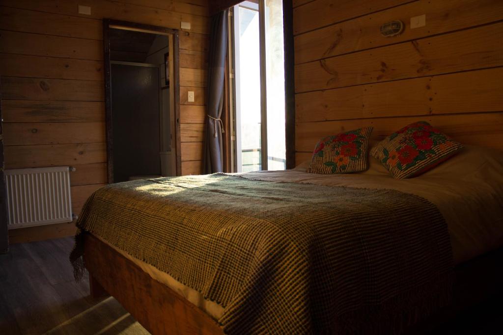 a bedroom with a bed in a wooden cabin at Hostal Dos Volcanes in Malalcahuello