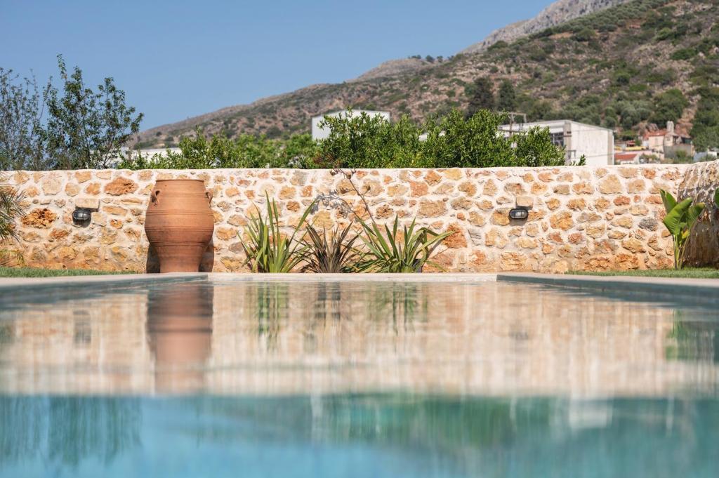 una piscina di fronte a un muro di pietra di Villa Eliomylos a Souda (Suda)