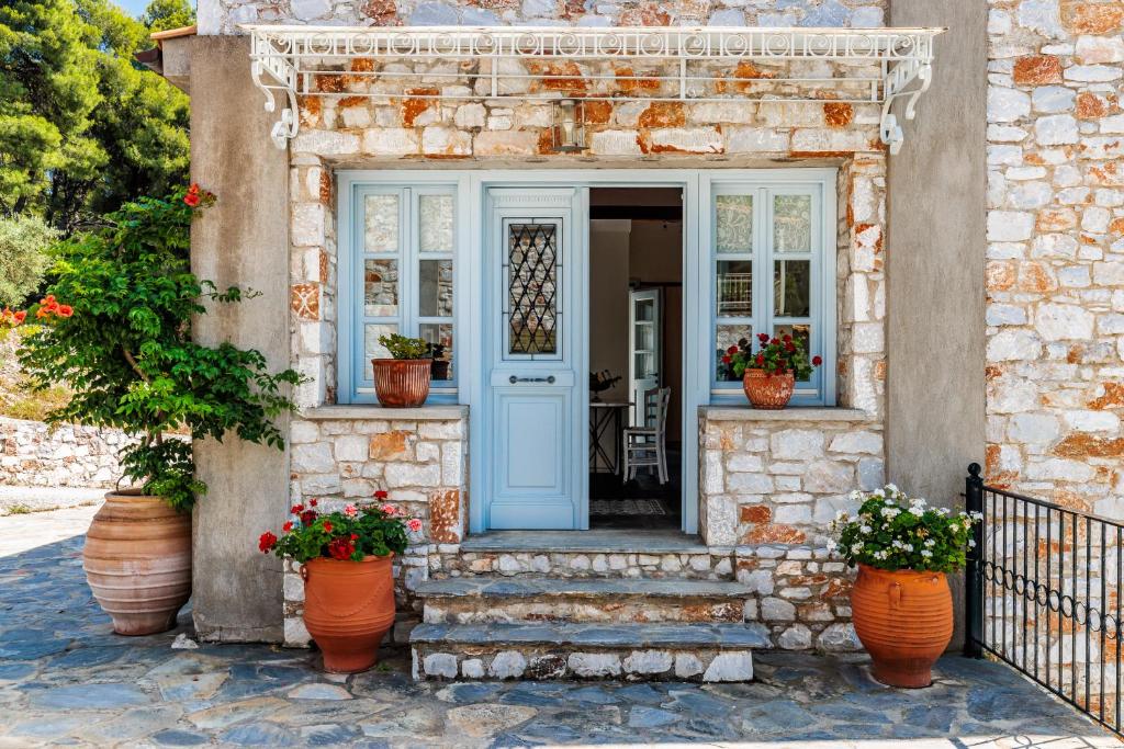 a stone house with a blue door and potted plants at Althea in Panormos Skopelos