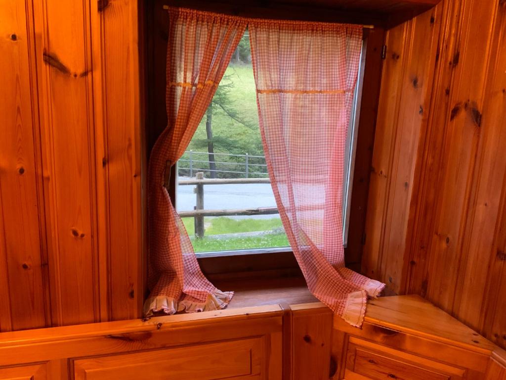 ein Fenster mit Vorhängen in einer Holzhütte in der Unterkunft La Meison in Valgrisenche