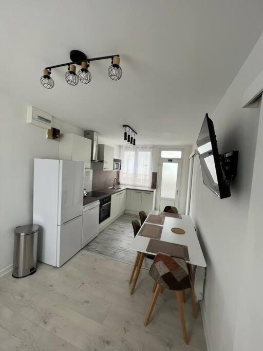 une cuisine avec une table et un réfrigérateur blanc dans l'établissement Appartement 3 pièces moderne 2 à 6 personnes, à La Bourboule