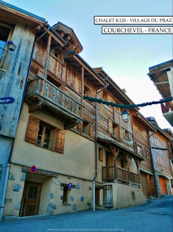 un vieux bâtiment avec des balcons en bois dans une rue dans l'établissement Chalet K120 - Village du Praz - Courchevel, à Courchevel