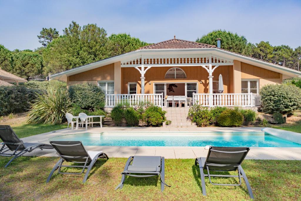 ein Haus mit Pool und Stühlen davor in der Unterkunft villa familiale dans cadre exceptionnel, piscine chauffée-AG19 in Lacanau