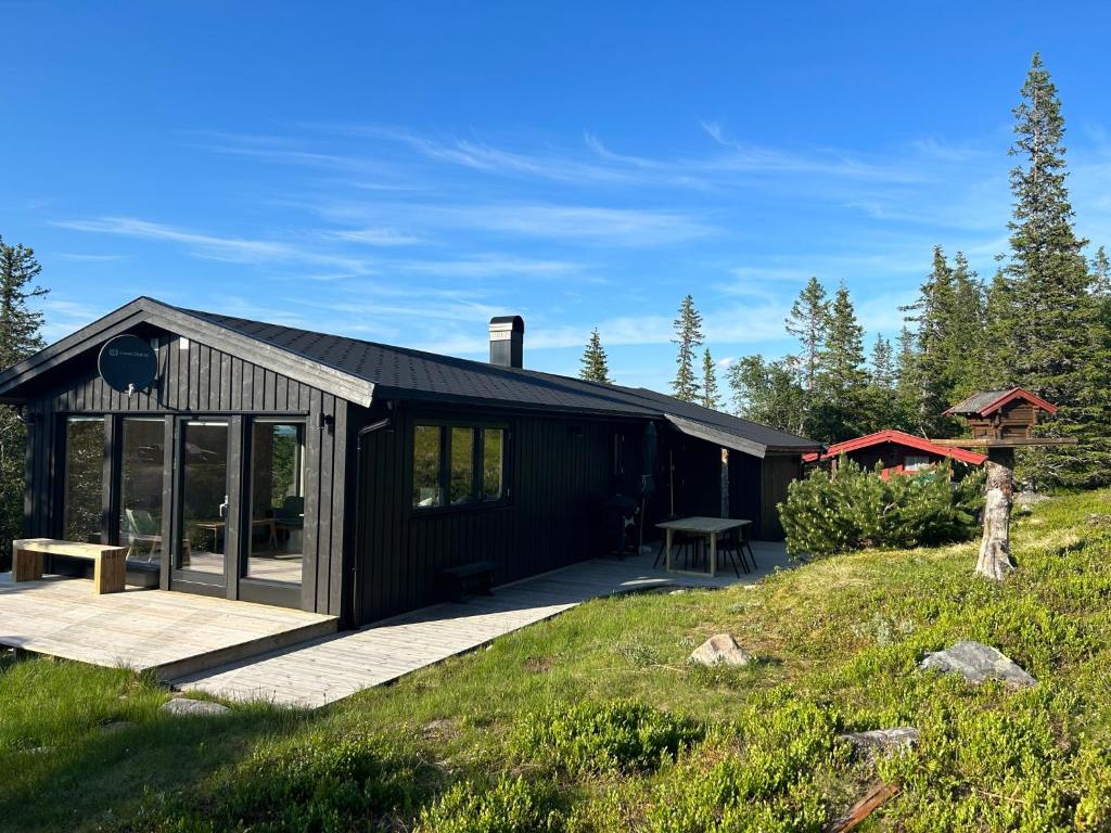 une cabine noire avec une terrasse couverte et une terrasse dans l'établissement Vegglihytta - cabin with a tranquil location, à Veggli