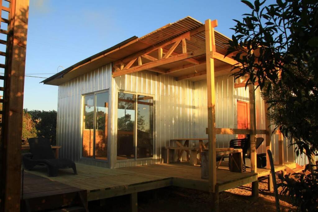 ein kleines Haus mit einer Holzterrasse und einem Tisch in der Unterkunft Cabañas Guanaqueros Arriendo Diario in Guanaqueros