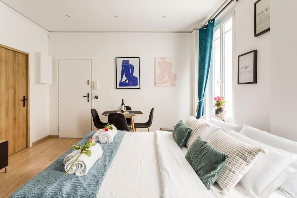 a white bedroom with a white bed and a table at Suite Paris, Tour Eiffel, Champs Elysées in Paris