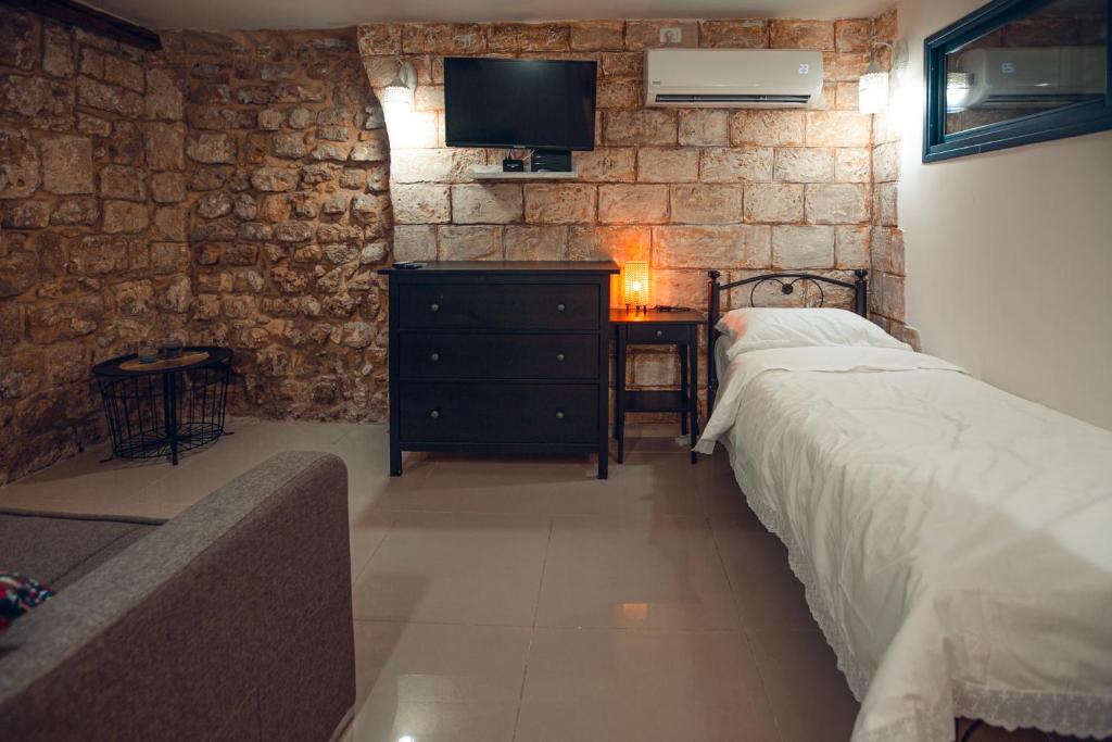 a bedroom with a bed and a dresser and a tv at Tony Guesthouse in Acre
