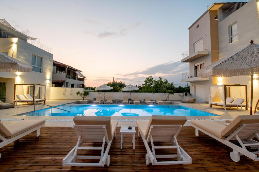uma piscina com cadeiras e uma mesa e um edifício em Ennea suites-Storm suite em Flámbouras