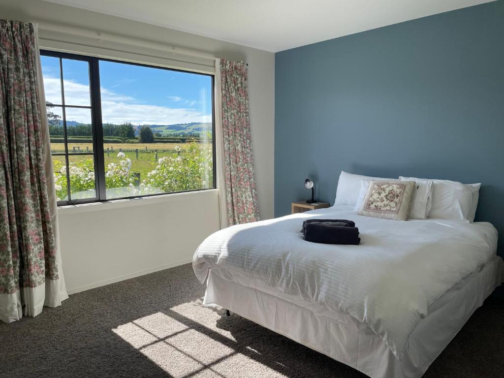 a bedroom with a bed and a large window at The Barn in Mosgiel