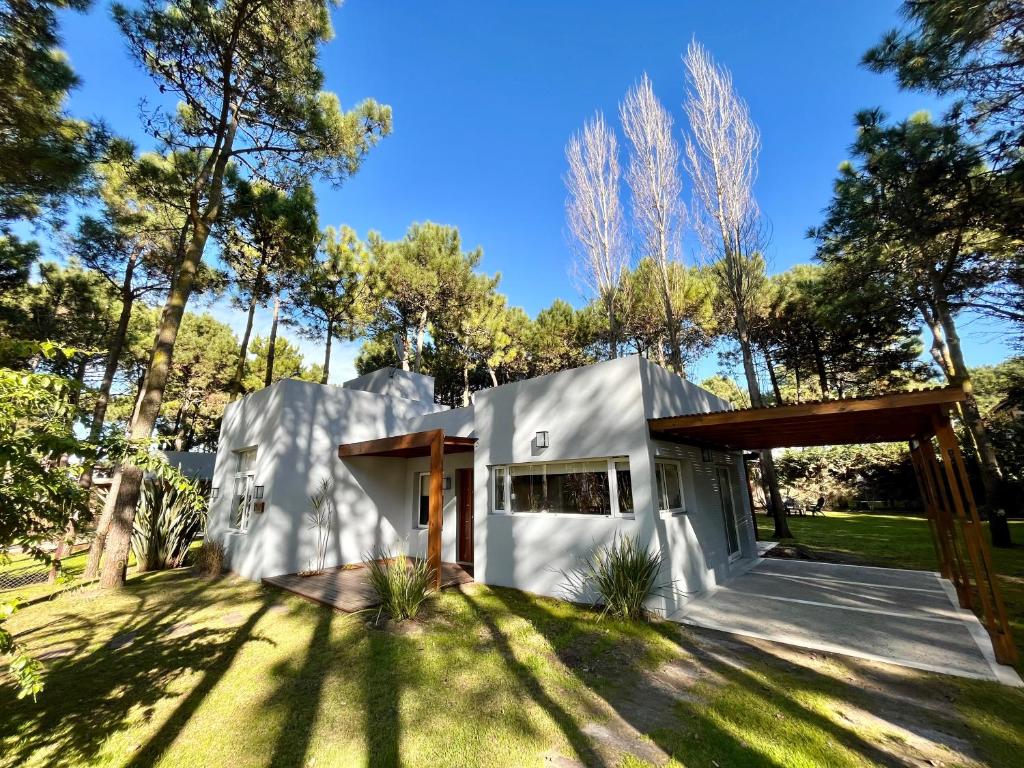 una casa en el bosque con una fachada blanca en Casa De Los Titanes, ideal para descansar! en Pinamar