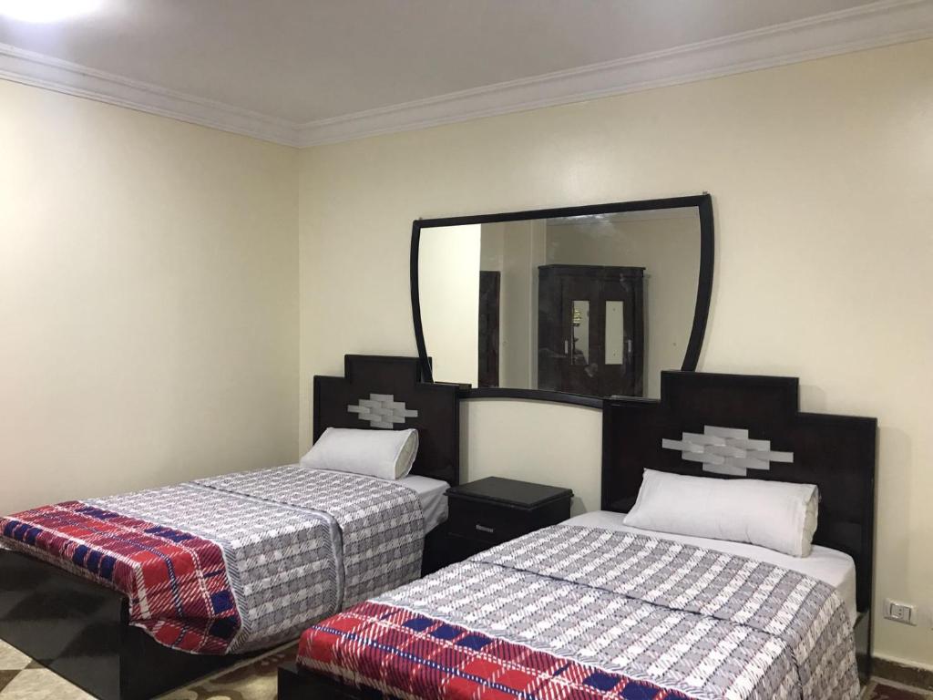 a bedroom with two beds and a mirror at Adam Pyramids in Cairo