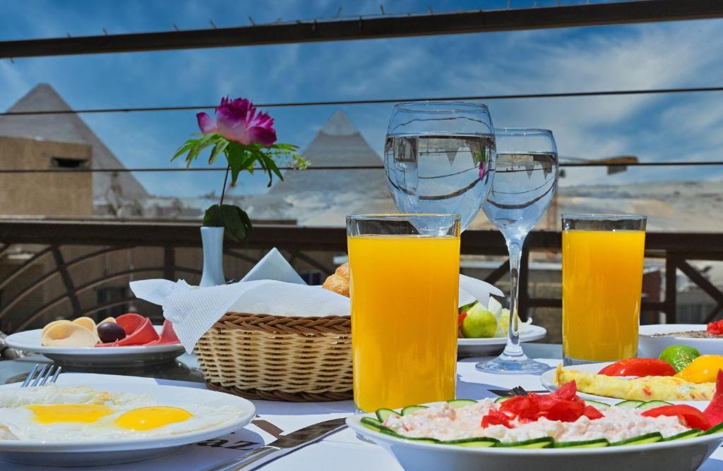 uma mesa com pratos de comida e copos de sumo de laranja em Pyramids Gem Plaza Hotel & Apartments no Cairo