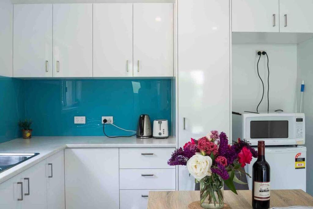 a kitchen with white cabinets and a vase of flowers at Garden-nestled granny flat between winery and town in Armidale
