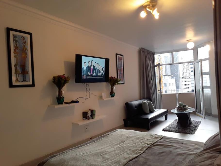 a bedroom with a bed and a chair and a window at 36 HydePark Apartments in Cape Town