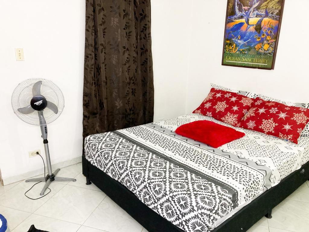 a bedroom with a bed with red pillows and a fan at BARU ESTELAR in Medellín