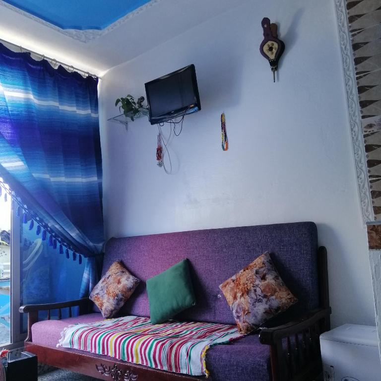 Elle comprend un canapé violet avec des oreillers et une télévision murale. dans l'établissement Casa Mar, à Chefchaouen